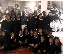 Seth Mazibuko with a group of student visitors. The young man smiling in the photograph behind him is Seth’s 17-year-old self, greeting supporters at his trial for “sedition and terrorism.” 